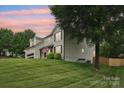 Exterior showcasing a well-maintained lawn, attached garage, and classic architecture at dusk at 207 Spaniel Se Dr, Concord, NC 28025