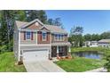 View of the attractive home near a tranquil pond, showing its blend of stone, siding, and landscaped lawn at 2527 Linhay Dr, Charlotte, NC 28216