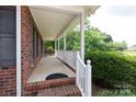 A covered porch with a brick base, white railings, and an outdoor swing at 328 Burrage Ne Rd, Concord, NC 28025