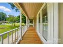 Long front porch with wood floors, white railing, and large windows overlooking the yard at 336 Oakwood Dr, Mount Holly, NC 28120