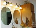 Bright bathroom featuring three decorative mirrors, updated lighting fixtures, and classic wooden cabinetry at 4492 Antelope Ln, Charlotte, NC 28269