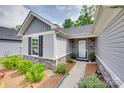 Inviting front entrance with a stone facade, grey siding, and lush landscaping at 4511 Hunton Dale Nw Rd, Concord, NC 28027