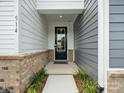 Close-up of the front door with black trim and sidelights, brick foundation, and gray siding at 507 Webster Ln, Cramerton, NC 28032