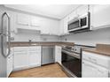 Well-lit kitchen with white cabinets, laminate floors, stainless steel appliances, and stainless steel sink at 10101 Wood Ct, Charlotte, NC 28277