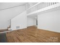Spacious living room featuring laminate flooring, white walls, and staircase leading to second floor at 10101 Wood Ct, Charlotte, NC 28277