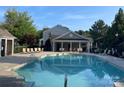 Community pool and pool house with seating and lounge chairs under a blue sky at 10135 Blakeney Preserve Dr, Charlotte, NC 28277