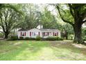 Quaint single-story home with red shutters surrounded by large, mature trees, creating a peaceful setting at 1270 N Enochville Ave, China Grove, NC 28023