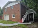 Backyard view featuring a brick exterior, upper deck access, and a one-car garage at 1660 Songwood Rd, Concord, NC 28025