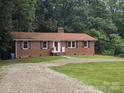 Charming brick home with black shutters and a red door, complemented by a gravel driveway and green lawn at 1660 Songwood Rd, Concord, NC 28025