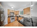 Well-lit kitchen featuring granite counters, stainless steel appliances, and wooden cabinetry at 201 N Dotger Ave # C8, Charlotte, NC 28207