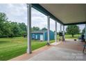 Covered back porch with grill, seating, and view of large lawn with detached outbuilding at 3103 Richview Dr, Crouse, NC 28033