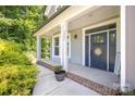 Inviting front porch featuring a blue door, white columns, and a brick-lined base at 3902 Mcgee Point Rd, Terrell, NC 28682