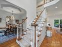 Elegant staircase with wood and white railing leads to upper level near dining room at 4644 Snow Dr, Harrisburg, NC 28075