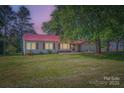 Lovely home with a red metal roof and a large front yard bathed in the warm glow of dusk at 8255 Castor Rd, Salisbury, NC 28146