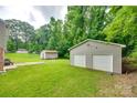 A spacious backyard showcasing a large garage with dual doors, additional storage shed, and lush greenery at 2111 Parkdale Ave, Gastonia, NC 28052