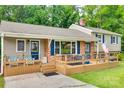 A cozy split-level home featuring brick accents, blue shutters, an inviting deck, and outdoor seating arrangements at 2111 Parkdale Ave, Gastonia, NC 28052