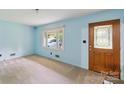 Bright living room with neutral carpet, light blue walls and a decorative wooden front door at 46 Donna Dale Se Ave, Concord, NC 28025