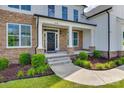 Charming front porch featuring stone accents, black front door, and manicured landscaping at 509 Abelia Ln, Fort Mill, SC 29708