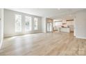Open-concept living space with hardwood floors, a view of a bright, all-white kitchen, and natural light at 509 Abelia Ln, Fort Mill, SC 29708