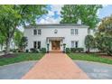 Charming two-story white brick home with mature trees, a brick driveway, and manicured landscaping at 601 Cherokee Rd, Charlotte, NC 28207