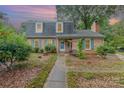 Charming two-story brick home with blue shutters and a landscaped front yard with a wooden porch swing at sunset at 6577 Stoney Ridge Rd, Matthews, NC 28104