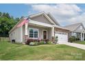 Cozy home with a welcoming front porch, American flag, and well-kept lawn at 7328 Strawberry Fields Ln, Charlotte, NC 28278