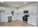Modern kitchen featuring white cabinets, stainless steel appliances, and light hardwood flooring, exuding a clean aesthetic at 823 32Nd Ne St, Conover, NC 28613