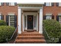 Inviting entryway with brick steps, elegant columns, and a stylish black door with a wreath at 9717 Waterton Ct, Huntersville, NC 28078