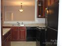 Functional kitchen features black appliances and a pass-through bar to the dining area at 9823 Hyde Glen Ct, Charlotte, NC 28262