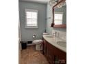 Bathroom featuring a double sink vanity, neutral tile flooring, and a large window at 106 Condover Pl, Charlotte, NC 28270