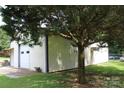 Exterior shot of a large outbuilding with a white exterior and a metal roof under a tree at 116 Woodbark Ln, Kings Mountain, NC 28086