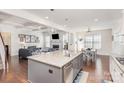 Open kitchen and living room with a large island with a sink, stainless appliances, and modern finishes at 11618 Macallano Dr, Charlotte, NC 28215