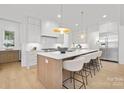 Bright kitchen with white cabinets, stainless steel appliances, island with seating, and pendant lights at 1321 Ferncliff Rd, Charlotte, NC 28211
