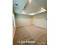 Expansive main bedroom with plush carpeting, tray ceiling and recessed lighting, offering a serene and luxurious retreat at 1598 Respect St, Concord, NC 28027