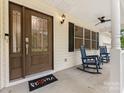 Covered porch boasts rocking chairs and decorative front door at 5322 Bridgeview Dr, Iron Station, NC 28080