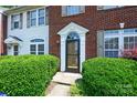 Brick townhome featuring a detailed front door, surrounded by lush greenery, and a well-maintained facade at 7007 Creft Cir, Indian Trail, NC 28079