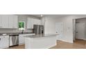 Kitchen featuring white cabinets, a granite island, stainless steel appliances, and hardwood floors at 7311 Jerimoth Dr, Charlotte, NC 28215
