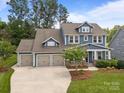 Aerial view of a charming two-story home with blue siding, landscaped yard, and a three-car garage at 11329 Fullerton Place Nw Dr, Huntersville, NC 28078
