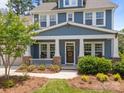 Charming front porch of blue home with white columns and railings, adorned with a wreath and rocking chairs at 11329 Fullerton Place Nw Dr, Huntersville, NC 28078
