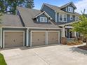 Three-car garage, blue siding, and a spacious driveway create an inviting entrance to this charming home at 11329 Fullerton Place Nw Dr, Huntersville, NC 28078