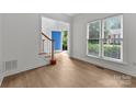 Bright entryway featuring hardwood floors, a staircase with wood banister, and natural light from a window at 15400 Groveland St, Huntersville, NC 28078