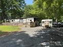 Well-maintained RV with wooden deck, a shed, and a picnic table on a lot with gravel and grassy areas at 155 Indian Harbor Trl # E243, Mount Gilead, NC 27306