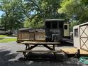 RV with outdoor seating, picnic table, and shed in wooded lot covered with gravel at 155 Indian Harbor Trl # E243, Mount Gilead, NC 27306