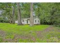 Landscaped front yard with mature trees surrounding the charming white home at 240 Swink Ave, Salisbury, NC 28147