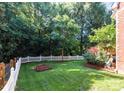 Private backyard featuring a white picket fence, mature trees, and a well-maintained lawn at 2504 Fallbrook Pl, Concord, NC 28027
