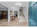 Bright foyer with hardwood floors, staircase, and elegant lighting fixture at 2917 Rustic Ln, Charlotte, NC 28210