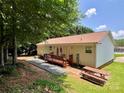 Backyard featuring a deck, brick patio, picnic table and gravel bed underneath a shady tree at 1031 Daniel Dr, Stanley, NC 28164