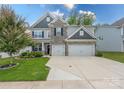 Charming two-story home featuring a stone facade, a three-car garage, and a manicured front yard at 1054 Thoroughbred Dr, Iron Station, NC 28080