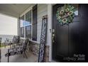 Charming front porch with decorative wreath, welcome sign, and chairs for outdoor seating at 1054 Thoroughbred Dr, Iron Station, NC 28080