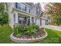 Charming front yard featuring a landscaped flower bed, well-maintained lawn, and covered front porch at 1054 Thoroughbred Dr, Iron Station, NC 28080